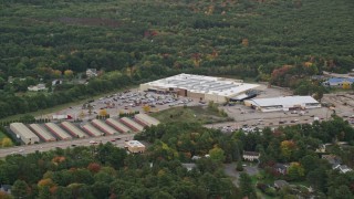 AX152_232 - 5.5K aerial stock footage flying by Walmart, surrounded by trees with partial fall foliage, Walpole, Massachusetts