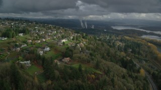 AX153_148 - 5.5K aerial stock footage flying over Highway 14 by suburban homes to approach paper mill in Camas, Washington