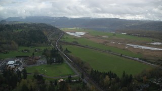 AX153_177 - 5.5K aerial stock footage flying by a train traveling by fields in Washougal, Washington
