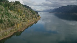 AX154_001E - 5.5K aerial stock footage of train tracks at the bottom of a cliff in Columbia River Gorge, Oregon