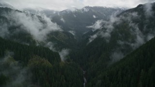 AX154_050E - 5.5K aerial stock footage following Eagle Creek Trail through a canyon with mist and forest in Cascade Range, Hood River County, Oregon