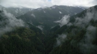 AX154_052 - 5.5K aerial stock footage flying through a misty canyon to approach a mountain ridge with snow in Cascade Range, Hood River County, Oregon