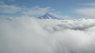 AX154_062 - 5.5K stock footage aerial video flying over thick cloud layer to approach snowy Mount Hood, Cascade Range, Oregon