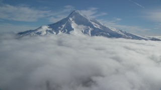 AX154_073 - 5.5K aerial stock footage flying over clouds to approach Mount Hood with snow, Mount Hood, Cascade Range, Oregon