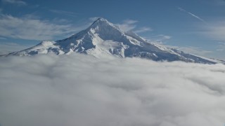 AX154_073E - 5.5K aerial stock footage flying over clouds to approach Mount Hood with snow, Mount Hood, Cascade Range, Oregon