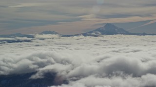 AX154_098E - 5.5K aerial stock footage of Mount Jefferson and the Three Sisters Volcanoes seen from across low clouds, Cascade Range, Oregon