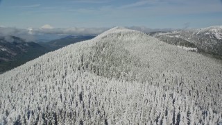 AX154_103E - 5.5K aerial stock footage flying over frozen forest on a mountain ridge, Cascade Range, Oregon