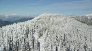 AX154_105 - 5.5K stock footage aerial video flying over a snow forest on top of a mountain ridge, Cascade Range, Oregon