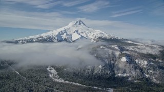 AX154_108E - 5.5K aerial stock footage of low clouds over snowy forest near Mount Hood, Cascade Range, Oregon