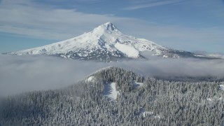 AX154_113 - 5.5K stock footage aerial video approaching a ridge, snowy forest and clouds near Mount Hood, Cascade Range, Oregon