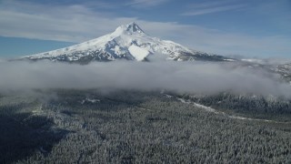 AX154_119 - 5.5K aerial stock footage of snow-capped peak and low clouds over forest, Mount Hood, Cascade Range, Oregon