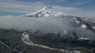 AX154_121 - 5.5K aerial stock footage of low clouds over forest and ridge near snow-capped Mount Hood, Cascade Range, Oregon