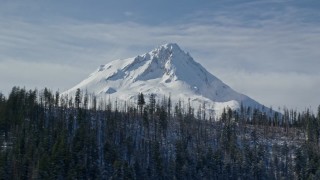AX154_125E - 5.5K aerial stock footage of mist rising from forest on ridge with snowy summit in background, Mount Hood, Cascade Range, Oregon