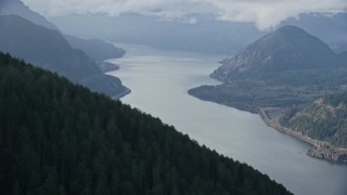AX154_153E - 5.5K aerial stock footage flying by evergreen forest on mountain to reveal the Columbia River Gorge, Hood River County, Oregon