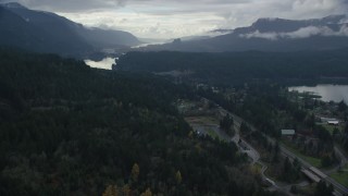 AX154_169 - 5.5K aerial stock footage flying over forest by Interstate 84 to approach Bridge of the Gods, Cascade Locks, Oregon in Columbia River Gorge