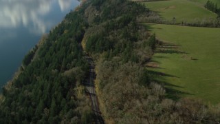 AX154_197 - 5.5K aerial stock footage of a bird's eye view of Highway 14 through forest, tilt to reveal an isolate home and green fields, Washougal, Washington