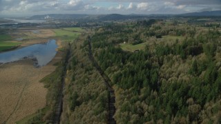 AX154_199 - 5.5K aerial stock footage flying over railroad tracks and Highway 14 through forest in Washougal, Washington