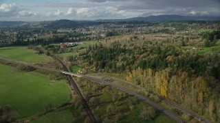 AX154_201 - 5.5K aerial stock footage flying over railroad tracks and Highway 14 beside forest near rural homes in Washougal, Washington