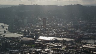 AX154_225E - 5.5K aerial stock footage of godrays coming down on Moda Center, the Willamette River and Downtown Portland, Oregon
