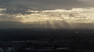 AX155_125 - 5.5K aerial stock footage of distant mountains and godrays from the clouds near Beaverton, Oregon, at sunset