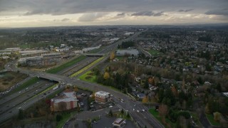 AX155_126E - 5.5K aerial stock footage flying over suburban homes to approach apartment buildings and follow Highway 26 in Beaverton, Oregon, twilight