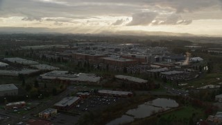 AX155_131 - 5.5K aerial stock footage passing Intel Ronler Acres with godrays in the background, in Hillsboro, Oregon, sunset