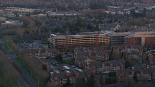 AX155_134 - 5.5K aerial stock footage flying by a large parking garage and the Kaiser Permanente Medical Offices at twilight in Hillsboro, Oregon