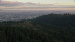 AX155_140 - 5.5K aerial stock footage of Mount Hood and Downtown Portland at sunset, seen from evergreen forest and hills in Northwest Portland, Oregon