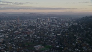 AX155_140E - 5.5K aerial stock footage of Mount Hood and Downtown Portland at sunset, seen from evergreen forest and hills in Northwest Portland, Oregon
