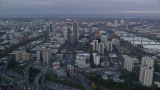 AX155_149E - 5.5K aerial stock footage orbiting skyscrapers and city streets near the Willamette River at twilight in Downtown Portland, Oregon