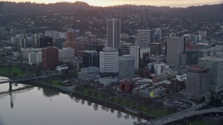 AX155_154E - 5.5K aerial stock footage of Downtown Portland skyscrapers and city park beside the Willamette River at twilight