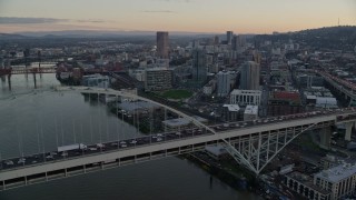 AX155_158E - 5.5K aerial stock footage orbiting heavy traffic crossing the Fremont Bridge at twilight, and reveal Downtown Portland, Oregon
