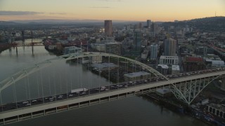 AX155_160 - 5.5K aerial stock footage of heavy traffic crossing the Fremont Bridge at twilight, and Downtown Portland skyscrapers in the background