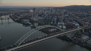 AX155_161E - 5.5K aerial stock footage fly over heavy traffic on the Fremont Bridge at twilight, Downtown Portland in the background, Oregon