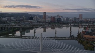 AX155_190E - 5.5K aerial stock footage of Downtown Portland skyline seen while flying by Willamette River bridges at twilight, Oregon