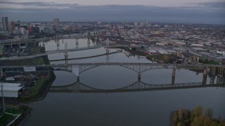 AX155_197E - 5.5K aerial stock footage of Ross Island Bridge and Willamette River bridges at twilight, reveal Downtown Portland, Oregon