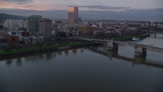 AX155_203 - 5.5K aerial stock footage flying over Morrison Bridge, and pass the waterfront park and downtown skyline at twilight, Downtown Portland, Oregon