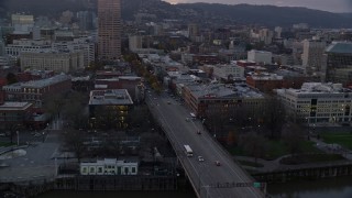 AX155_204E - 5.5K aerial stock footage flying over Burnside Bridge, and pass the White Stag sign at twilight, Downtown Portland, Oregon