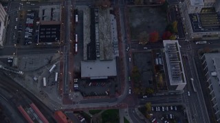 AX155_221 - 5.5K aerial stock footage of a bird's eye view of bus station and downtown buildings between NW 5th and 6th Avenue at twilight, Downtown Portland, Oregon