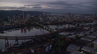 AX155_249E - 5.5K aerial stock footage of Downtown skyscrapers and bridges over the Willamette River at twilight, Downtown Portland, Oregon