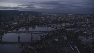 AX155_251 - 5.5K aerial stock footage flying by skyscrapers and bridges over the Willamette River at twilight, Downtown Portland, Oregon