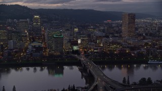 AX155_253 - 5.5K aerial stock footage passing skyscrapers and the Morrison Bridge over the Willamette River at twilight, Downtown Portland, Oregon