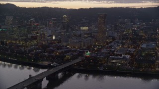 AX155_254E - 5.5K aerial stock footage of US Bancorp Tower, Burnside Bridge over the Willamette River, and White Stag Sign at twilight, Downtown Portland, Oregon