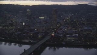 AX155_255 - 5.5K stock footage aerial video of the Burnside Bridge over the Willamette River, White Stag Sign, US Bancorp Tower at twilight, Downtown Portland, Oregon