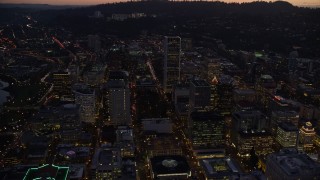 AX155_263E - 5.5K aerial stock footage following SW 3rd and 4th Avenues to approach KOIN Center and Wells Fargo Center at twilight, Downtown Portland, Oregon