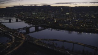 AX155_278 - 5.5K stock footage aerial video approaching freeway interchange, Willamette River, Burnside Bridge, and Downtown Portland, Oregon at twilight