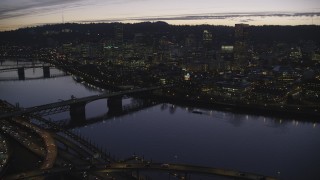 AX155_279 - 5.5K stock footage aerial video crossing the Willamette River to approach Burnside Bridge, White Stag sign, and Downtown Portland at twilight, Oregon