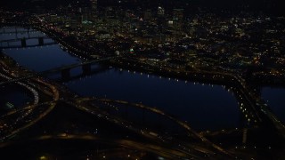 AX155_297 - 5.5K stock footage aerial video of Downtown skyscrapers, Willamette River bridges, freeway interchange, and White Stag sign at night, Downtown Portland, Oregon