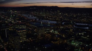 AX155_299E - 5.5K aerial stock footage flying over convention center to approach the Willamette River and Downtown Portland at night in Oregon