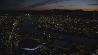 AX155_313 - 5.5K aerial stock footage flying over Moda Center, Memorial Coliseum by the Willamette River, with a view of Downtown Portland, Oregon, night